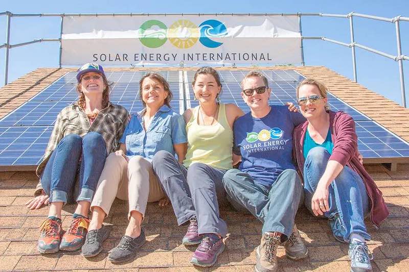 women sitting on roof in front of SEI banner